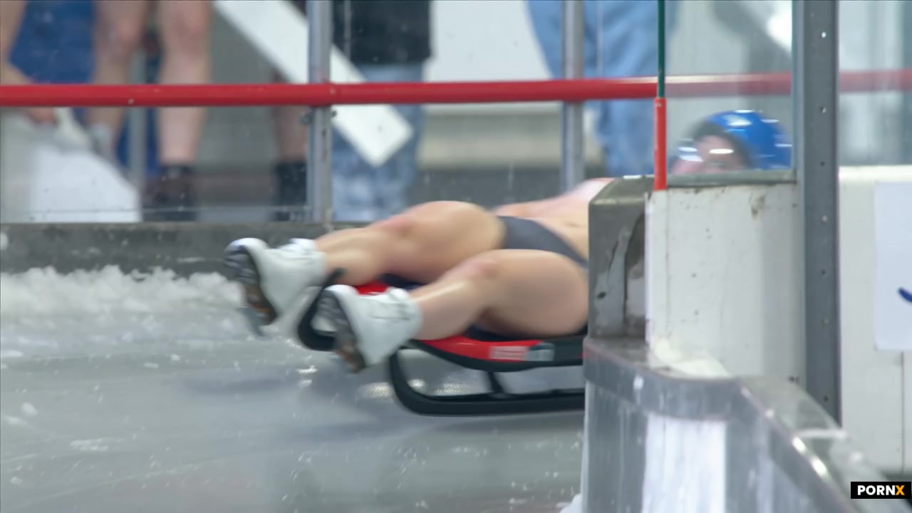 scene_description: A professional nude female luge athlete speeds down an Olympic ice track at extre